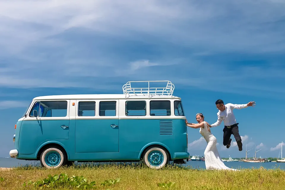 Brautpaar springt vor einem türkisen VW-Bus in die Luft